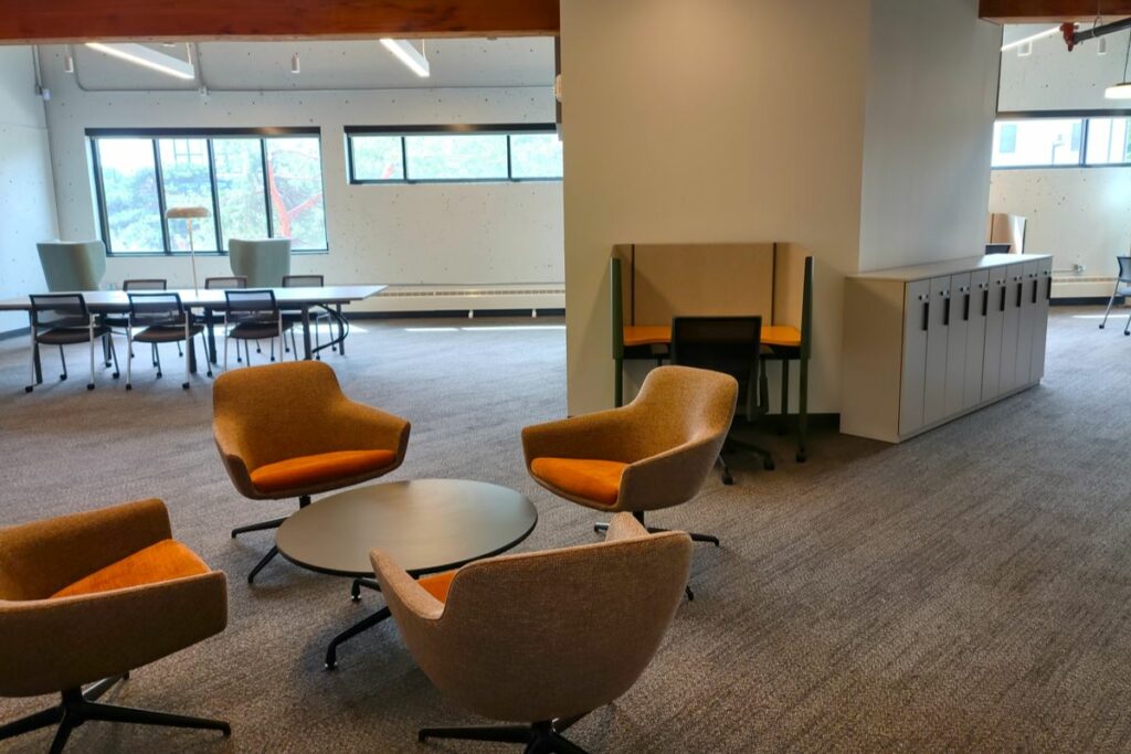 An open concept office space filled with comfy meeting chairs and desks.
