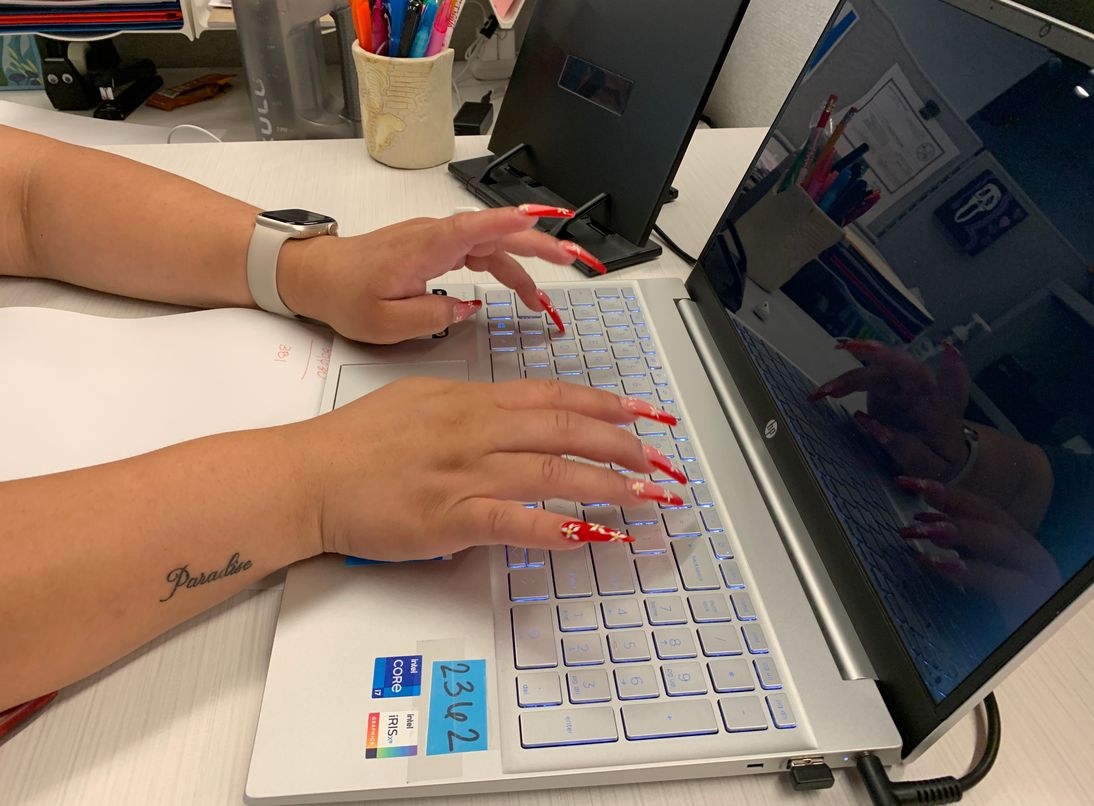 A woman types on a laptop. Her hands are visible as they type on a keyboard.