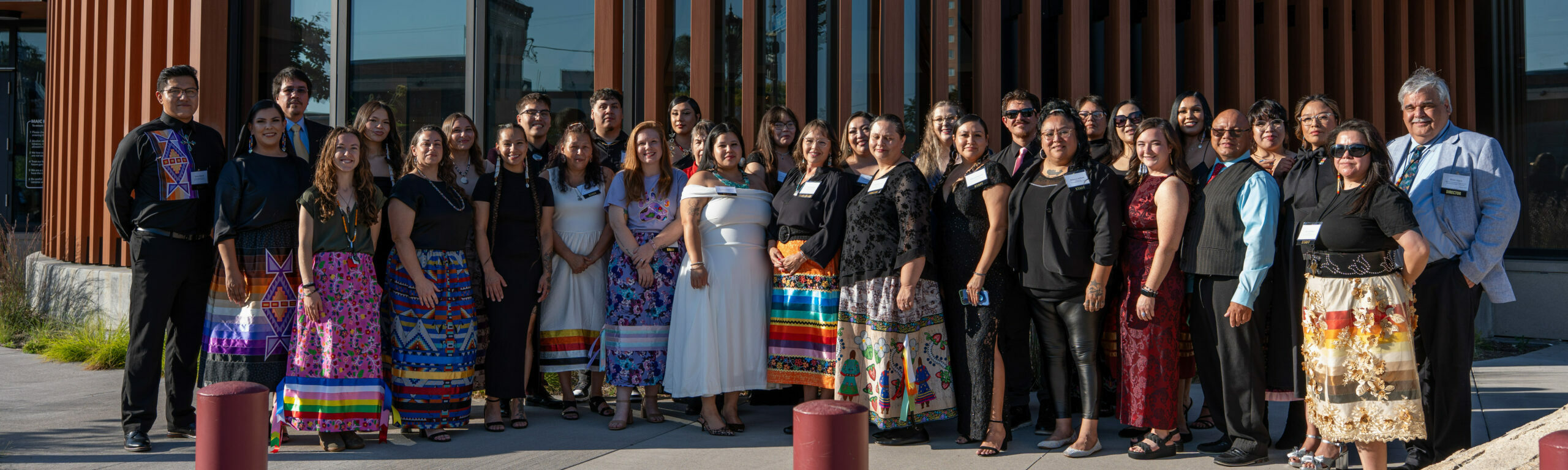 Staff smile for a photo in front of the Minneapolis American Indian Center building.