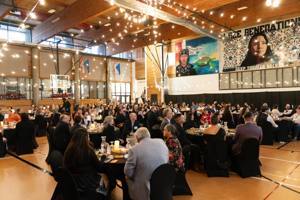 A decorated gym space with hanging lights and people in fancy clothes.